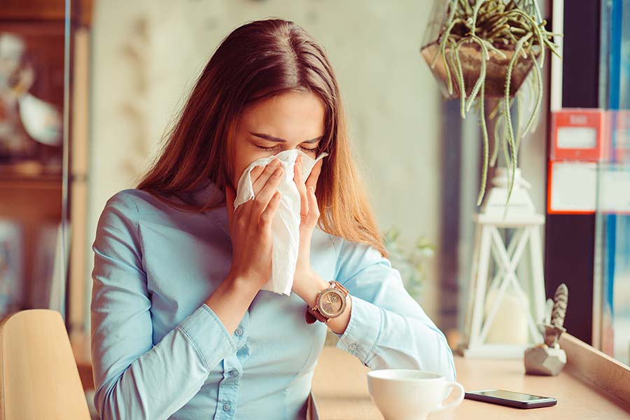 A woman with allergies. Sneezing can be one of many spring allergy symptoms during seasonal allergies