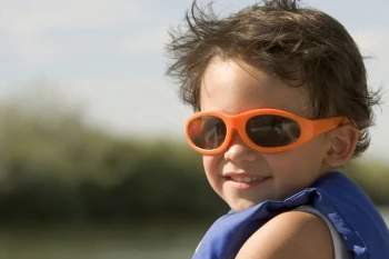 Child wearing sunglasses for eye protection from UV rays