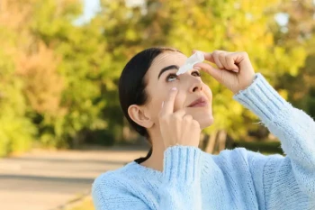 A woman treats her eyes for allergies.
