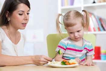 A little girl doesn't want to eat food her mother likes.