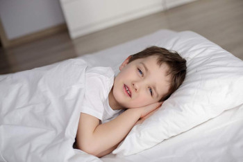 A boy sleeps with his eyes open.