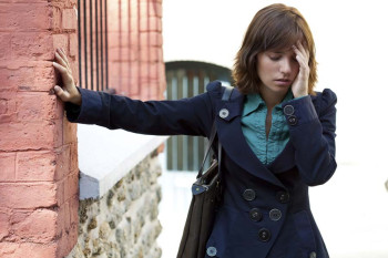 Dizzy woman balances against a wall