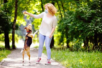 Woman with allergies playing with dog outside while wearing a face mask