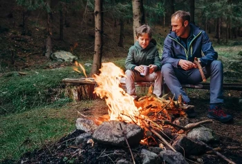 A father and son use proper campfire safety