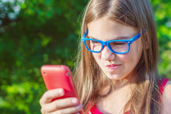 A teenager looks at her nose.