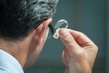 Man holding one of many hearing aid options