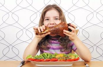 A little girl eats turkey