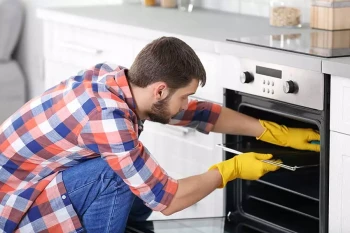 A man uses cleaning products to clean his oven
