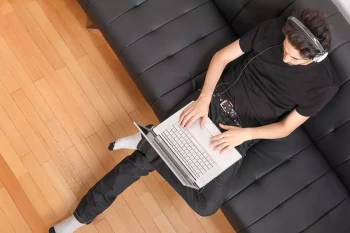 A man uses his laptop while sitting on his couch