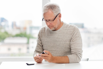 A man with glasses does a diabetes test