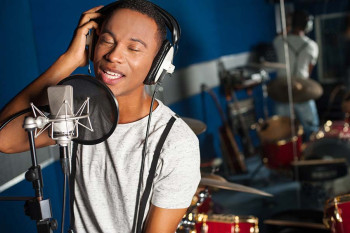 A man listens to himself sing in a recording studio