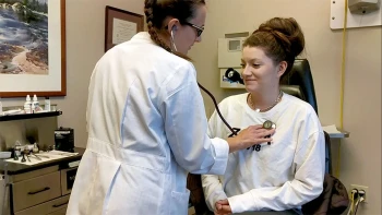 A physician assistant examines a patient.