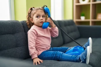 Toddler holding telephone near face