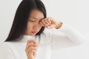 Woman scratching itchy eyes, it is one of many pink eye symptoms