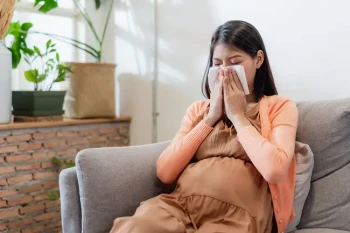A pregnant woman blows her nose. Pregnancy and stuffy nose can be connected through rhinitis