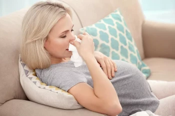 A pregnant woman blows her nose. Pregnancy and stuffy nose can be connected through rhinitis