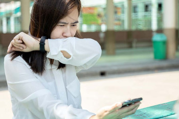 A woman with allergies, not coronavirus, sneezes safely.