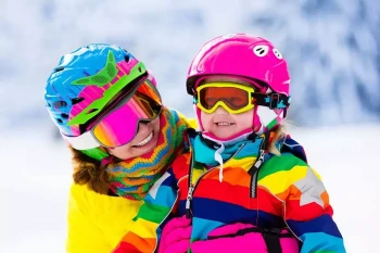 A mother and child wear goggles to protect their eyes while skiing