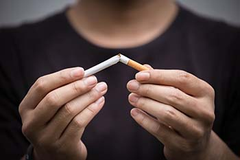 Man breaking cigarette, smoking and nicotine can have many effects on your eyes