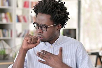 A man holds his chest because he has esophagitis, or throat pain when swallowing.