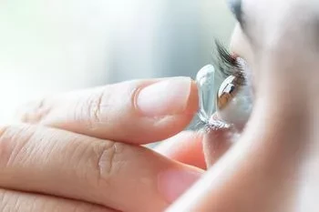Woman placing contact lens in her eye