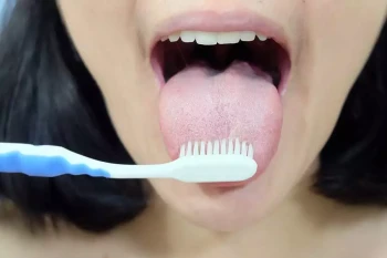 A woman with good oral hygiene brushes her tongue looking to avoid hairy tongue