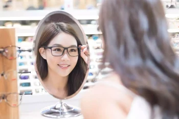 A woman tries on prescription glasses at an optical shop