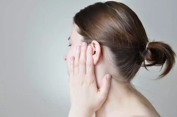A woman holds her injured ear.