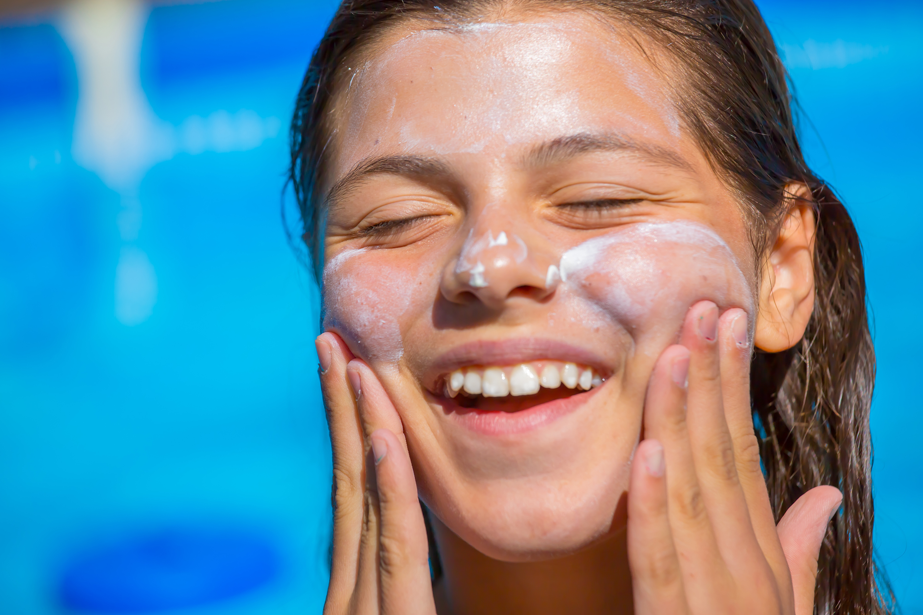 A woman applies sunscreen to the skin around her eyes.