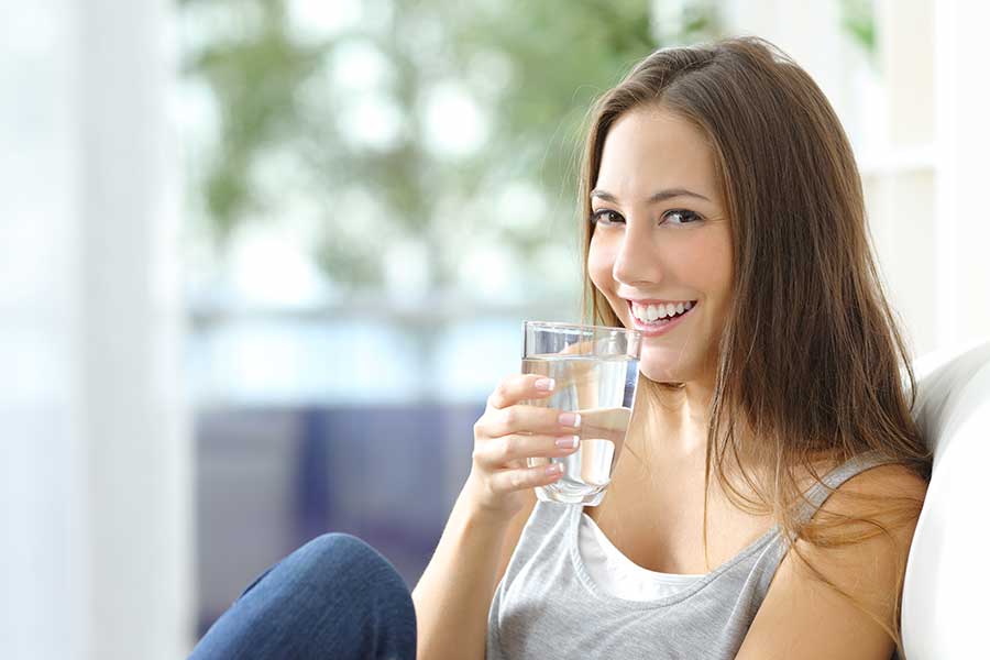 A woman drinks water, which is good for the voice