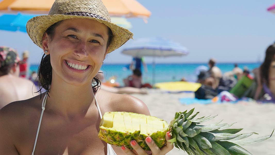 A woman holds a pineapple, which is one of several allergy foods for symptoms